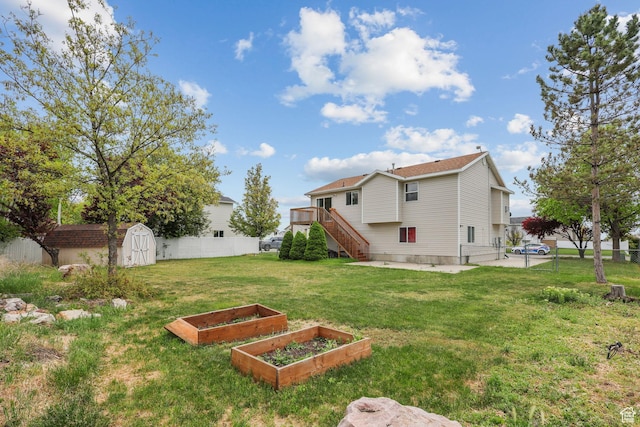 view of yard featuring fence, an outdoor structure, stairs, a garden, and a storage unit