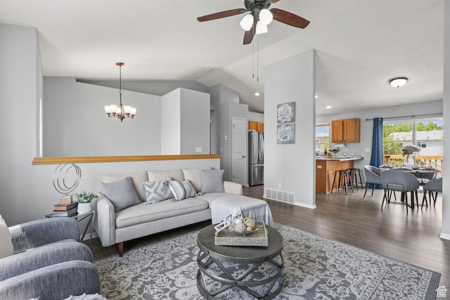 living room with lofted ceiling, ceiling fan with notable chandelier, visible vents, dark wood-style flooring, and baseboards