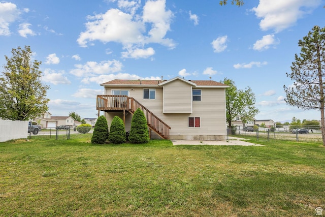 back of property with stairway, a fenced backyard, and a lawn