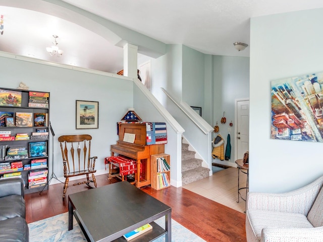 living area featuring stairway, decorative columns, and wood finished floors