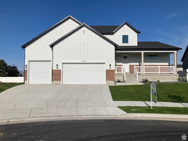 2882 S Allison Way W, Syracuse, UT 84075 - view of front of home featuring an attached garage, a front yard, board and batten siding, concrete driveway, and a porch