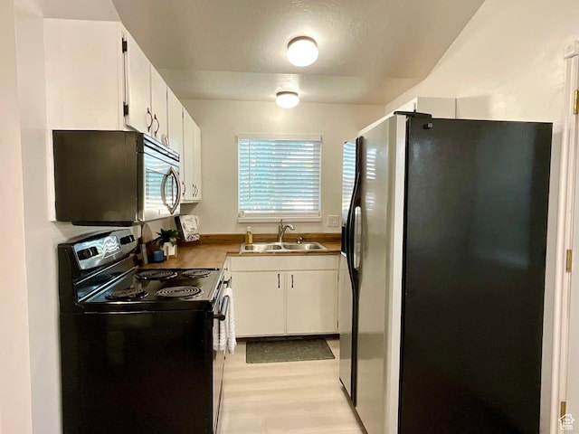2610 S 8000 W, Magna, UT 84044 - kitchen with freestanding refrigerator, black electric range oven, a sink, white cabinetry, and light wood-style floors
