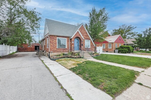 173 W 300 N, Bountiful, UT 84010 - tudor-style house featuring brick siding, a shingled roof, driveway, and central AC