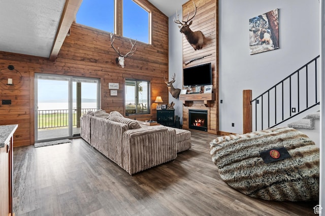 1504 N Sculpin Loop, Garden City, UT 84028 - living room featuring stairs, wood walls, high vaulted ceiling, and a lit fireplace