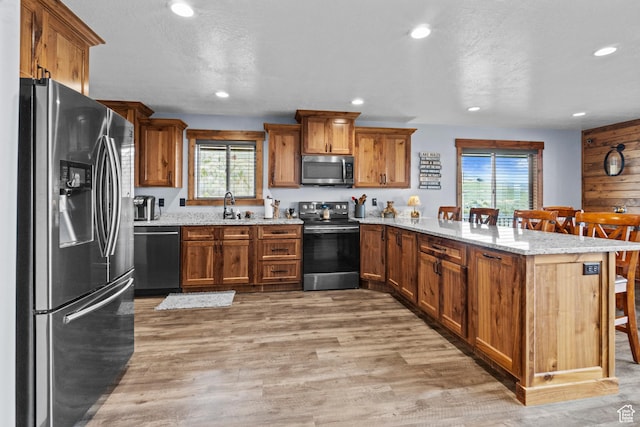 1504 N Sculpin Loop, Garden City, UT 84028 - kitchen with recessed lighting, brown cabinetry, a sink, a peninsula, and stainless steel appliances