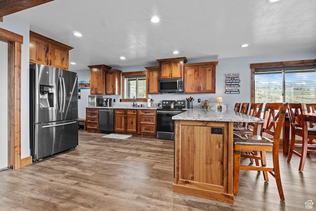 1504 N Sculpin Loop, Garden City, UT 84028 - kitchen featuring appliances with stainless steel finishes, brown cabinets, wood finished floors, and a breakfast bar