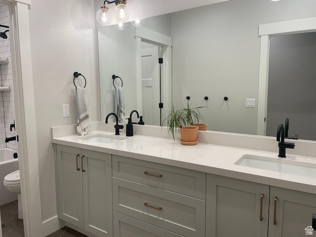 full bathroom with a sink, double vanity, toilet, and tile patterned floors