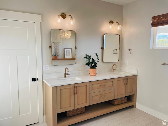 full bath with baseboards, tile patterned floors, double vanity, and a sink