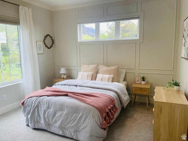 bedroom featuring carpet flooring, multiple windows, and a decorative wall