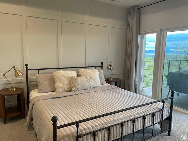 bedroom with carpet flooring, a decorative wall, and access to exterior
