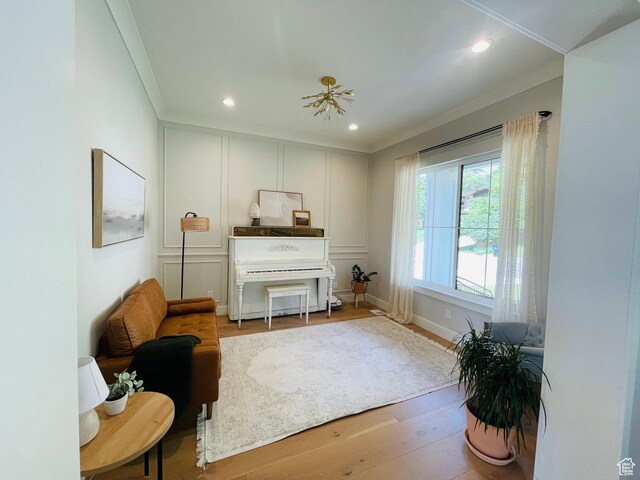 living area with a decorative wall, crown molding, wood finished floors, and recessed lighting
