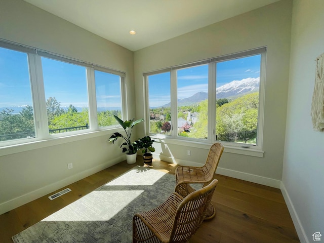 sunroom / solarium featuring a mountain view, visible vents, baseboards, and wood-type flooring