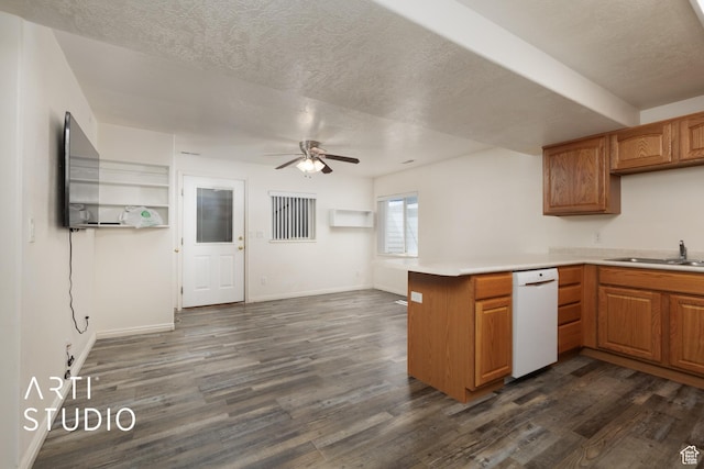 kitchen with a peninsula, dishwasher, dark wood-type flooring, and a sink