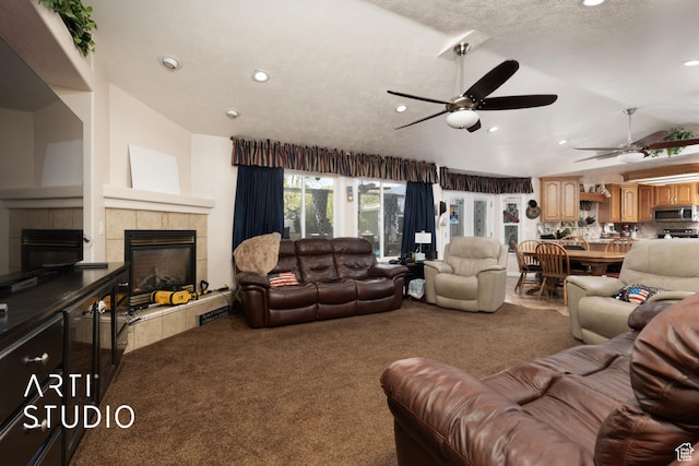 living room featuring carpet flooring, a tiled fireplace, lofted ceiling, and ceiling fan