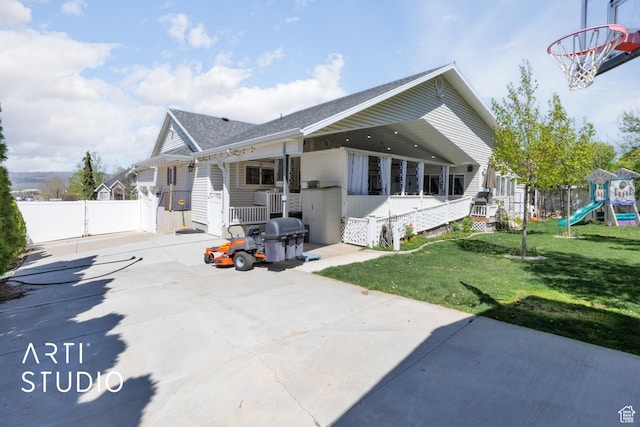 view of front facade featuring a gate, roof with shingles, fence, a front yard, and a playground