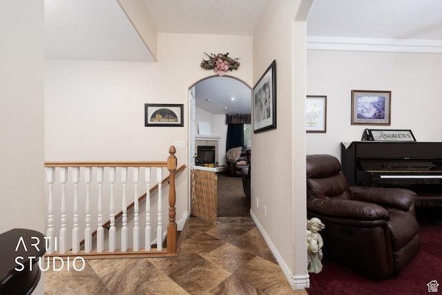 hallway with arched walkways, baseboards, and an upstairs landing