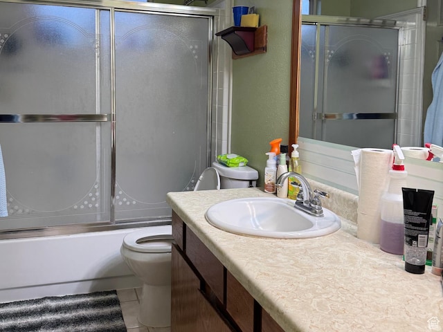 bathroom featuring toilet, bath / shower combo with glass door, tile patterned flooring, vanity, and a textured wall