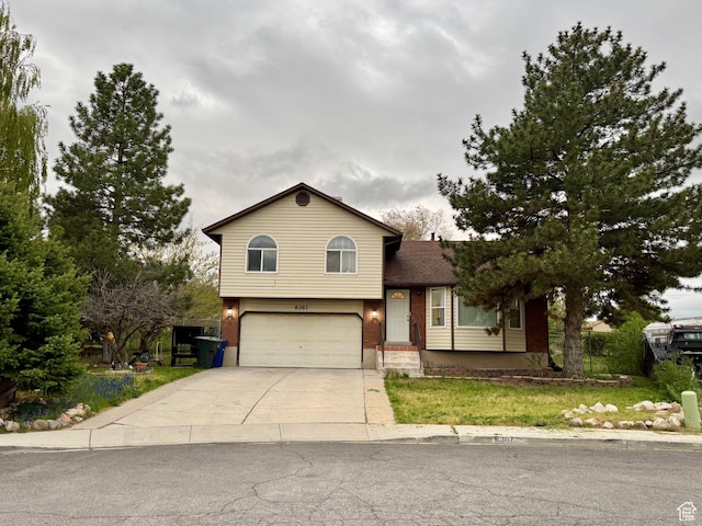 split level home with concrete driveway, brick siding, and a garage