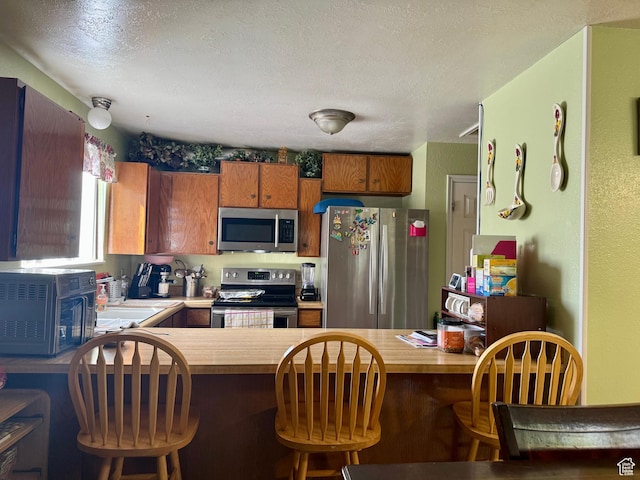 6367 W 4180 S, West Valley City, UT 84128 - kitchen featuring appliances with stainless steel finishes, a peninsula, a textured ceiling, and wooden counters