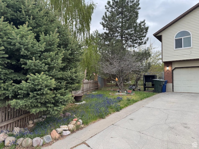 view of yard featuring an attached garage, driveway, and fence
