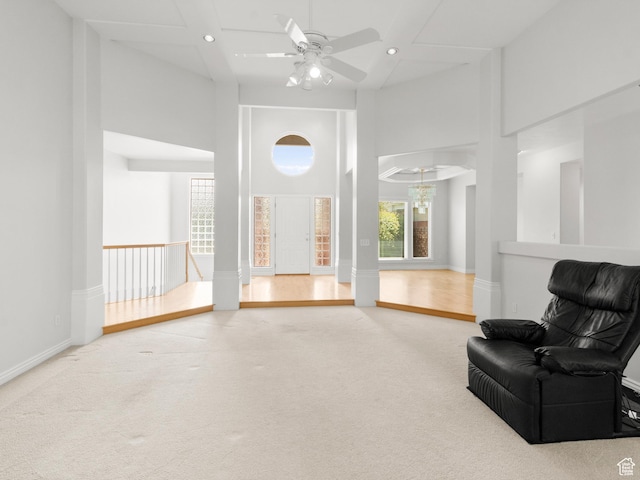 living area with a towering ceiling, carpet flooring, recessed lighting, ceiling fan, and baseboards