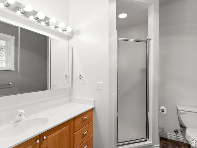 bathroom featuring toilet, a shower stall, and vanity
