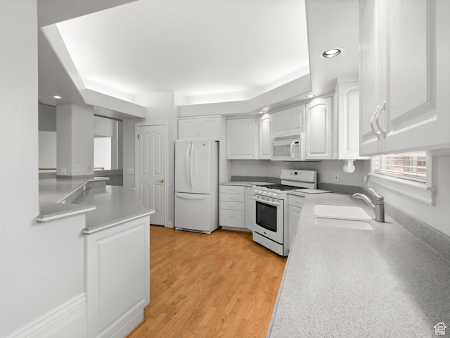 kitchen featuring white appliances, a sink, white cabinetry, recessed lighting, and light countertops