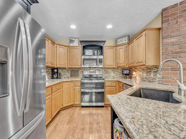 4760 S Meadow Creek Ln E, Ogden, UT 84403 - kitchen with appliances with stainless steel finishes, a sink, light wood-type flooring, light stone countertops, and tasteful backsplash
