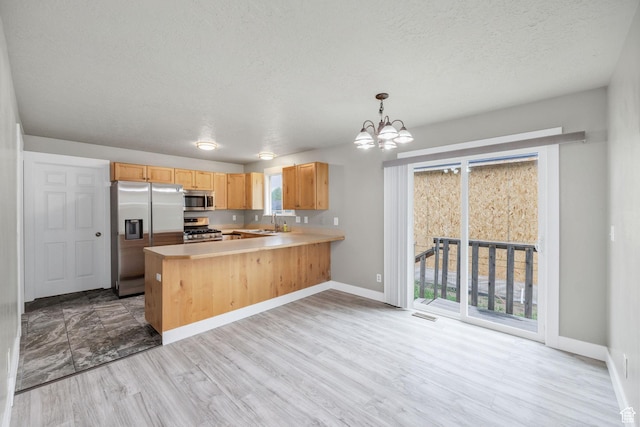 739 N 500 E, Logan, UT 84321 - kitchen with stainless steel appliances, a textured ceiling, a chandelier, light countertops, and a peninsula