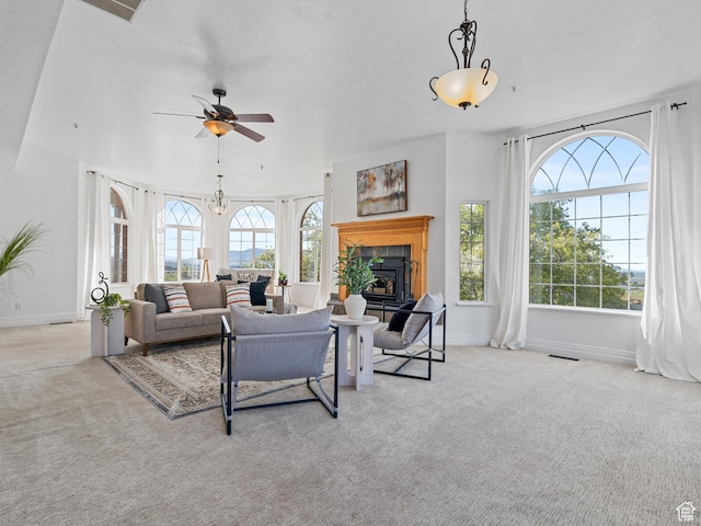 living area with carpet floors, ceiling fan, a fireplace with raised hearth, and baseboards