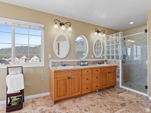 full bathroom with a mountain view, a stall shower, double vanity, and baseboards