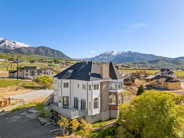 view of side of property featuring a balcony, a chimney, and a mountain view