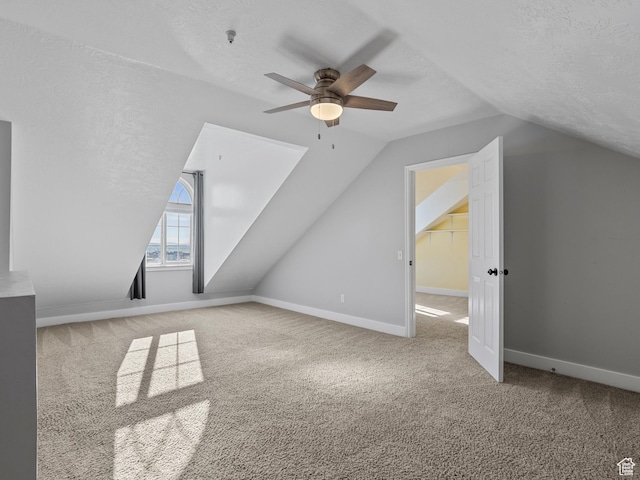 additional living space with vaulted ceiling, ceiling fan, carpet flooring, a textured ceiling, and baseboards