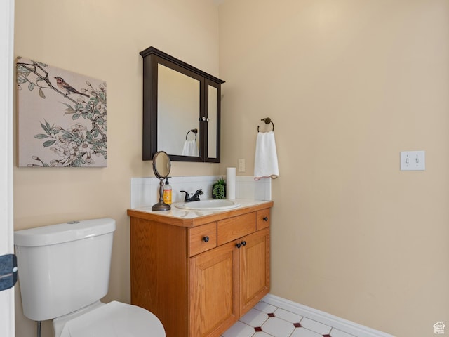 bathroom with toilet, vanity, tile patterned floors, and baseboards