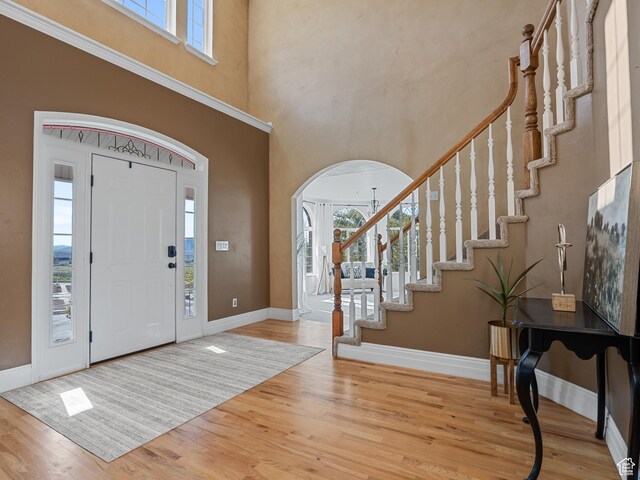 entrance foyer featuring arched walkways, wood finished floors, healthy amount of natural light, and a towering ceiling