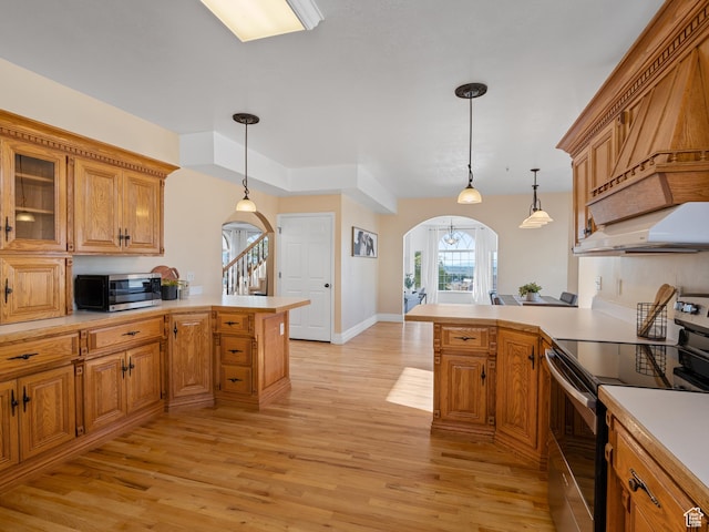 kitchen with appliances with stainless steel finishes, a peninsula, arched walkways, and light countertops