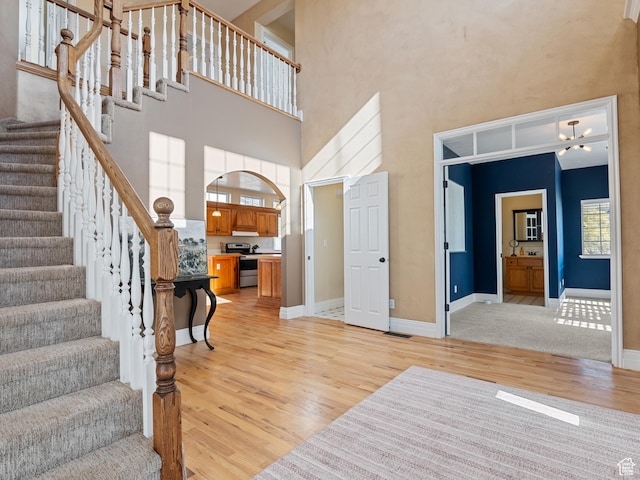 foyer entrance with light wood finished floors, a high ceiling, stairs, and baseboards