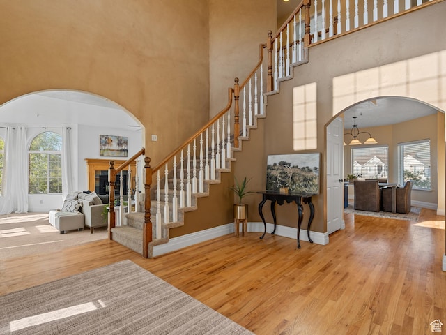 foyer entrance featuring arched walkways, wood finished floors, a high ceiling, stairway, and baseboards