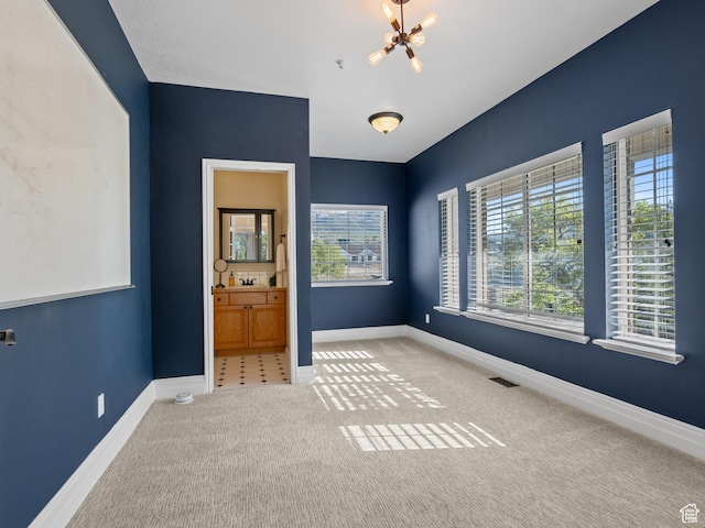 carpeted spare room with a chandelier and baseboards