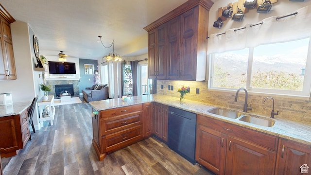 kitchen with dishwasher, a sink, a tiled fireplace, dark wood finished floors, and backsplash