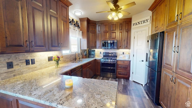 kitchen featuring stainless steel appliances, a sink, light stone counters, and ceiling fan
