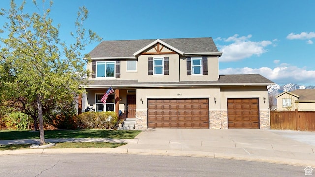 craftsman inspired home with stucco siding, stone siding, fence, and driveway