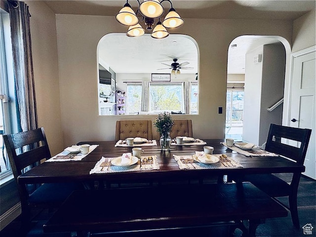 dining room featuring arched walkways, healthy amount of natural light, a ceiling fan, and a chandelier