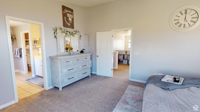 bedroom with light colored carpet, baseboards, light tile patterned floors, and ensuite bathroom