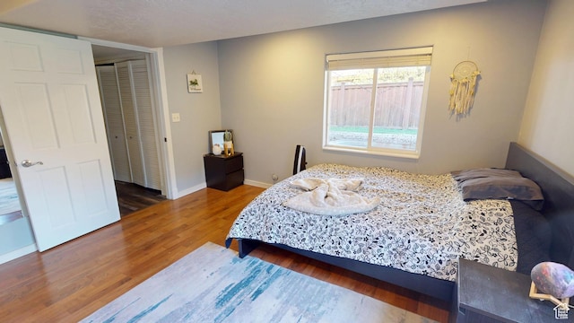 bedroom featuring wood finished floors, baseboards, and a closet
