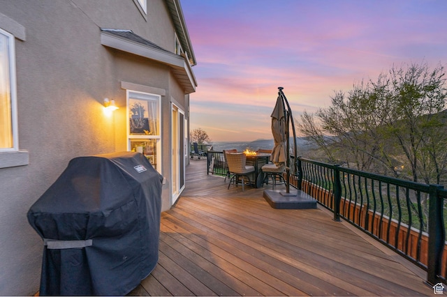 deck at dusk featuring outdoor dining area and a grill