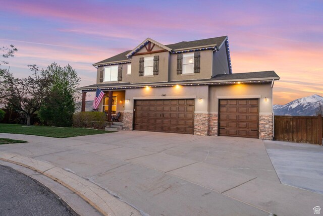 view of front of house with stone siding, stucco siding, driveway, and an attached garage