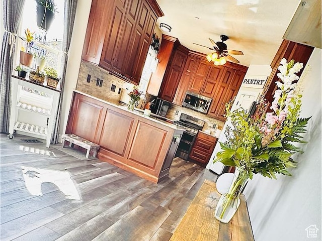 kitchen with appliances with stainless steel finishes, tasteful backsplash, ceiling fan, light countertops, and wood finished floors