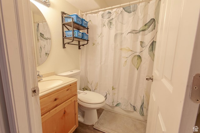 bathroom with toilet, vanity, and wood finished floors