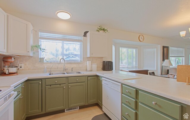 kitchen featuring white dishwasher, a sink, green cabinets, and light countertops
